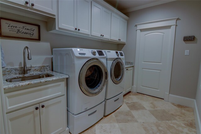 clothes washing area with crown molding, washer and dryer, light tile floors, sink, and cabinets