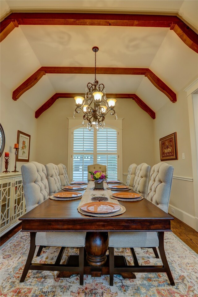 dining space with a notable chandelier, vaulted ceiling, and hardwood / wood-style floors