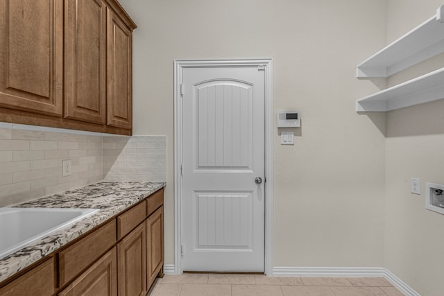 washroom featuring washer hookup, cabinets, and light tile patterned flooring