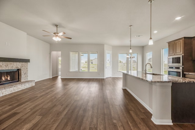 kitchen featuring light stone countertops, stainless steel appliances, sink, dark hardwood / wood-style flooring, and hanging light fixtures