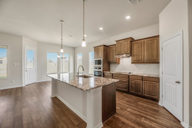 kitchen featuring an island with sink, tasteful backsplash, sink, dark hardwood / wood-style flooring, and appliances with stainless steel finishes