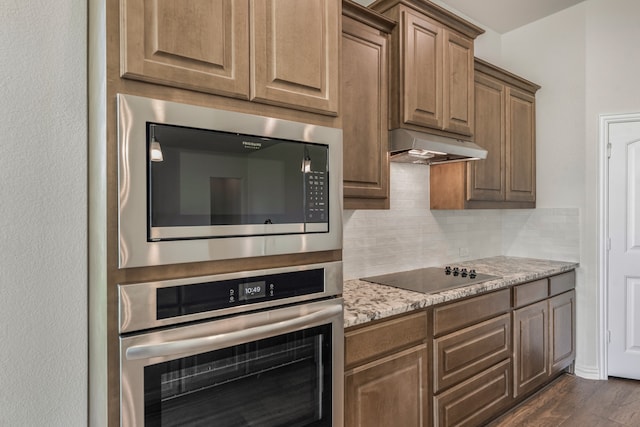 kitchen featuring appliances with stainless steel finishes, light stone counters, dark hardwood / wood-style floors, and backsplash