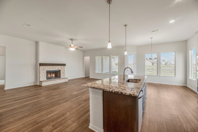 kitchen with hanging light fixtures, sink, a center island with sink, hardwood / wood-style flooring, and ceiling fan with notable chandelier