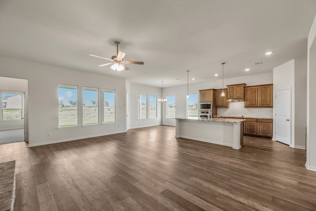 kitchen with hanging light fixtures, a center island with sink, dark hardwood / wood-style flooring, and a healthy amount of sunlight