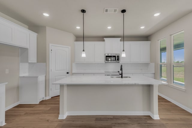 kitchen with light wood-type flooring, tasteful backsplash, sink, and white cabinetry