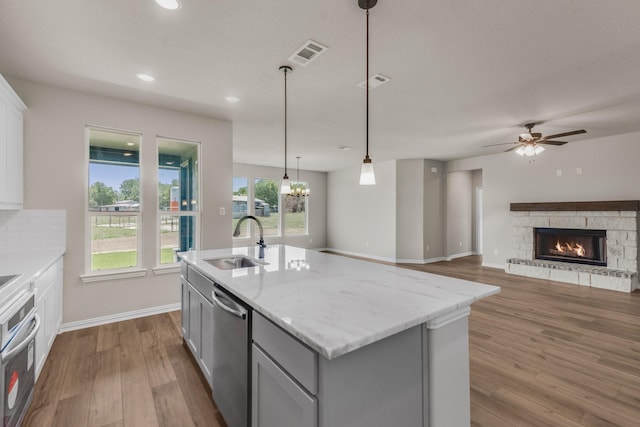 kitchen featuring gray cabinetry, stainless steel appliances, a sink, visible vents, and dark wood-style floors