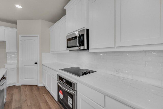 kitchen featuring appliances with stainless steel finishes, light wood-type flooring, tasteful backsplash, and white cabinets