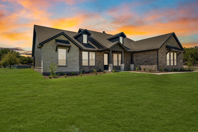 view of front facade with stone siding, a shingled roof, and a front yard