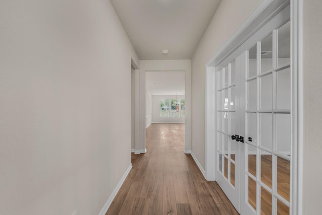 corridor with french doors, baseboards, and wood finished floors