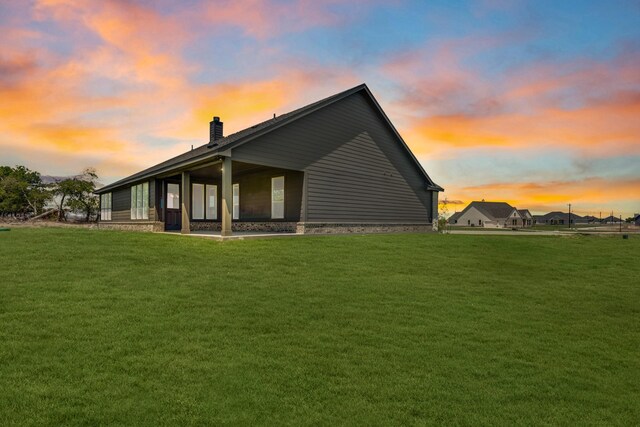 property exterior at dusk featuring a yard