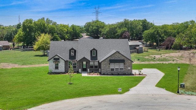 view of front facade with a front yard, roof with shingles, driveway, and fence