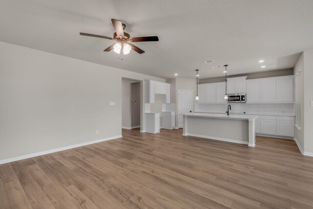 unfurnished living room featuring ceiling fan, sink, and light hardwood / wood-style floors