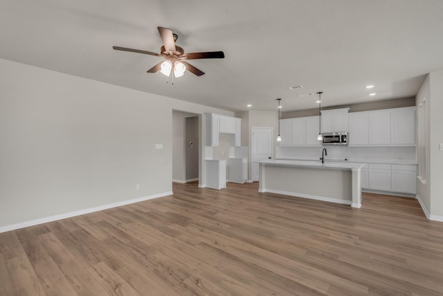 unfurnished living room with light wood-style floors, recessed lighting, baseboards, and a ceiling fan