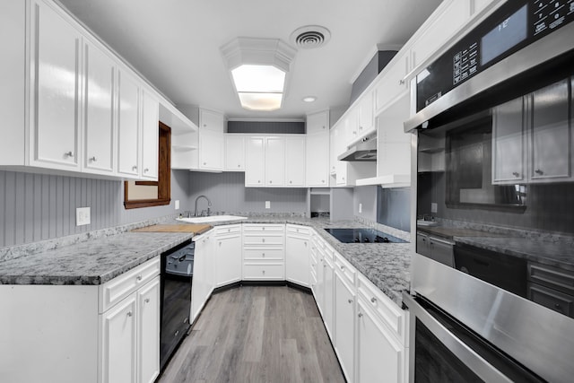 kitchen with light hardwood / wood-style floors, white cabinetry, light stone countertops, black appliances, and sink