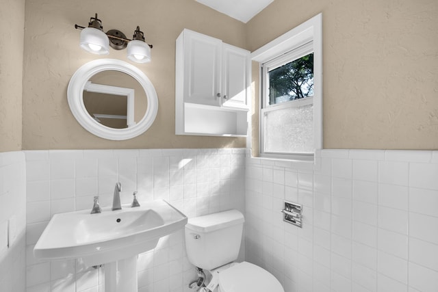 bathroom featuring sink, backsplash, toilet, and tile walls