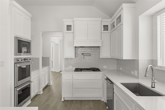 kitchen with stainless steel appliances, white cabinets, hardwood / wood-style floors, sink, and backsplash