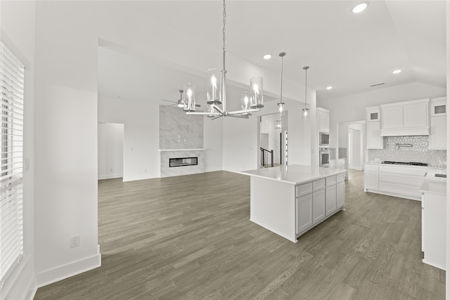 kitchen featuring white cabinets, pendant lighting, wood-type flooring, and a large fireplace