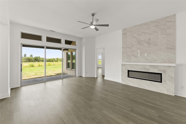 unfurnished living room with a fireplace, dark hardwood / wood-style floors, ceiling fan, and tile walls