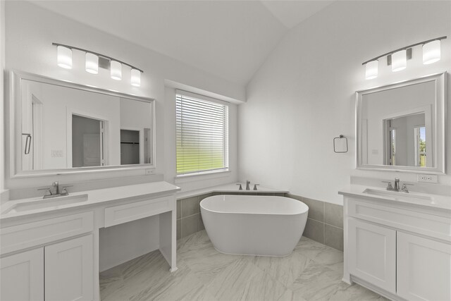 bathroom with vaulted ceiling, a bath, vanity, and tile walls