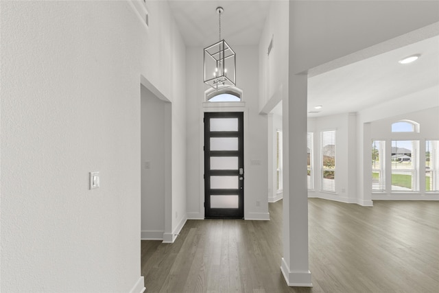 entryway with dark hardwood / wood-style flooring, a high ceiling, and an inviting chandelier