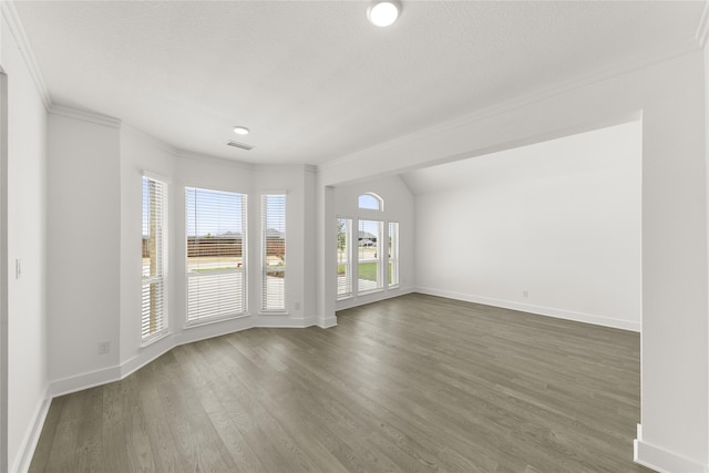 empty room featuring ornamental molding, a textured ceiling, and dark hardwood / wood-style flooring