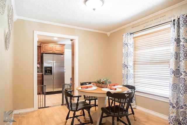 dining area with light hardwood / wood-style floors, a healthy amount of sunlight, a textured ceiling, and crown molding