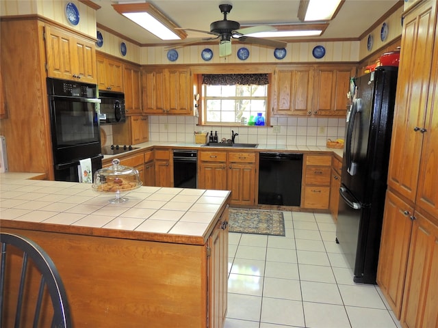 kitchen featuring kitchen peninsula, backsplash, ceiling fan, black appliances, and tile counters