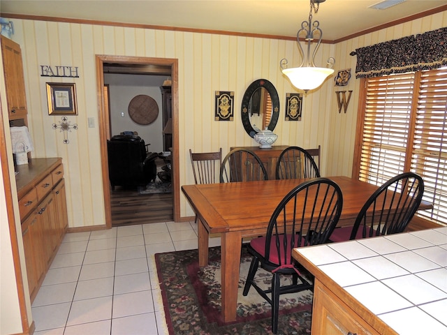 dining area with crown molding and light tile flooring