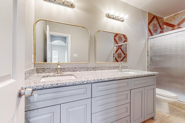 bathroom featuring toilet, tile patterned floors, vanity, and a shower with door