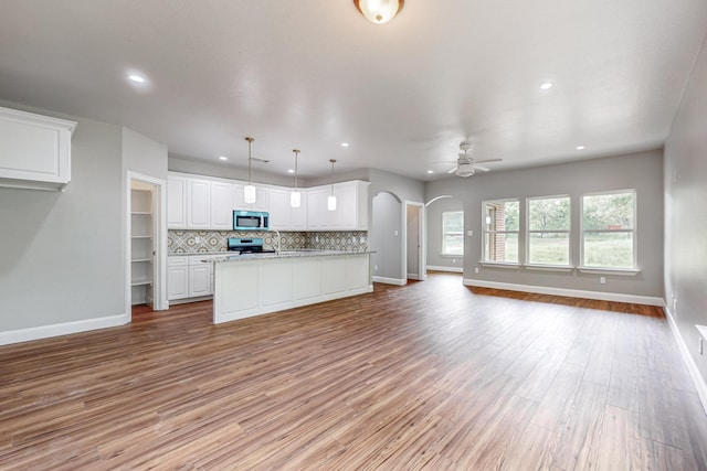 kitchen with white cabinetry, decorative light fixtures, light hardwood / wood-style floors, stainless steel appliances, and tasteful backsplash