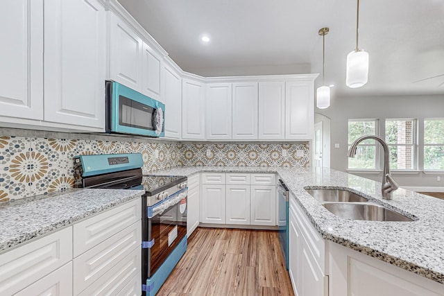 kitchen featuring sink, hanging light fixtures, white cabinetry, and stainless steel appliances