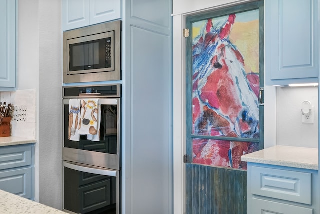 kitchen with appliances with stainless steel finishes, light stone counters, and blue cabinets