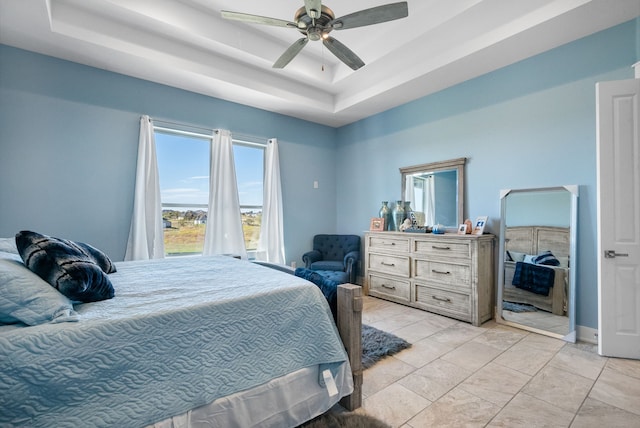 tiled bedroom with ceiling fan and a raised ceiling