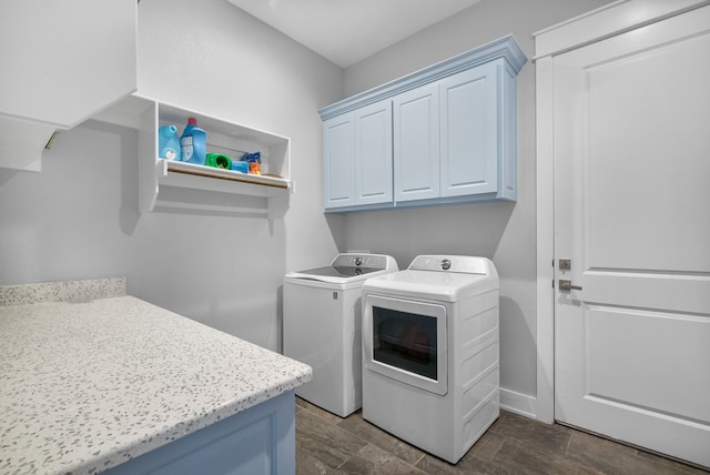 clothes washing area featuring washing machine and dryer, dark tile flooring, and cabinets