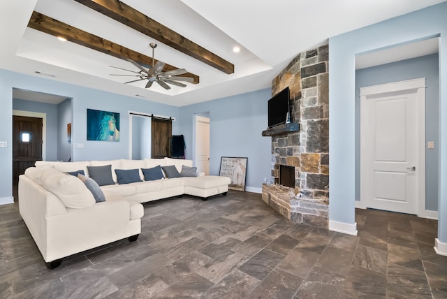 tiled living room with a fireplace, a tray ceiling, ceiling fan, a barn door, and beam ceiling