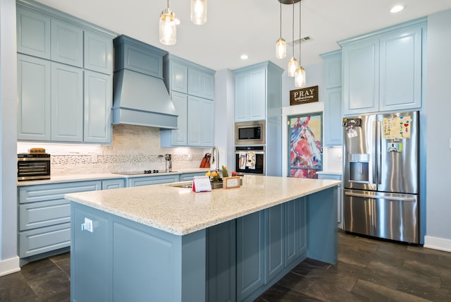 kitchen featuring custom range hood, a center island with sink, tasteful backsplash, appliances with stainless steel finishes, and pendant lighting