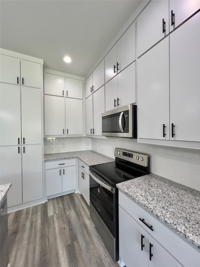 kitchen featuring tasteful backsplash, light wood-type flooring, white cabinetry, and appliances with stainless steel finishes