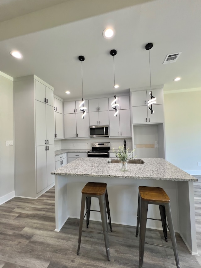 kitchen with hanging light fixtures, stainless steel appliances, light stone counters, wood-type flooring, and sink