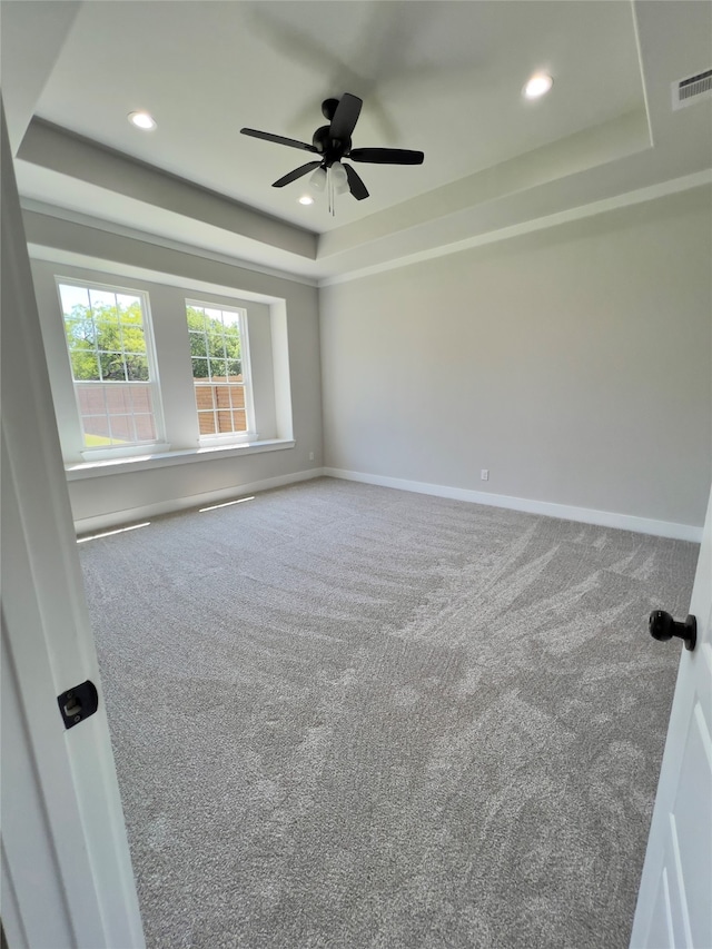 carpeted empty room featuring ceiling fan and a tray ceiling