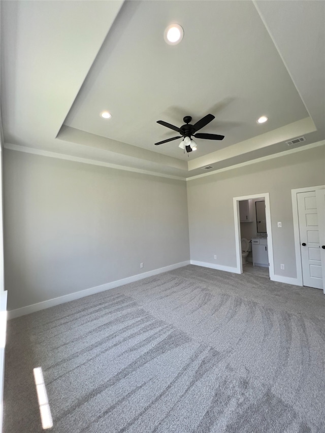 unfurnished bedroom with a tray ceiling, carpet floors, and ceiling fan