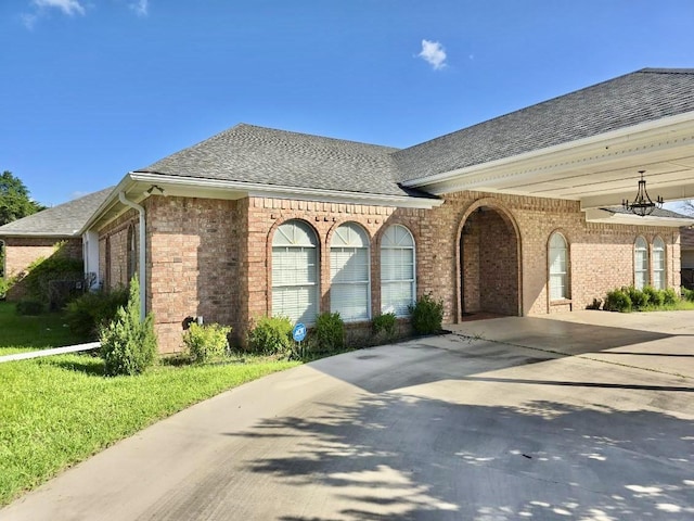 view of front of house featuring driveway, a shingled roof, and brick siding