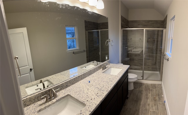 bathroom with vaulted ceiling, dual bowl vanity, toilet, wood-type flooring, and walk in shower