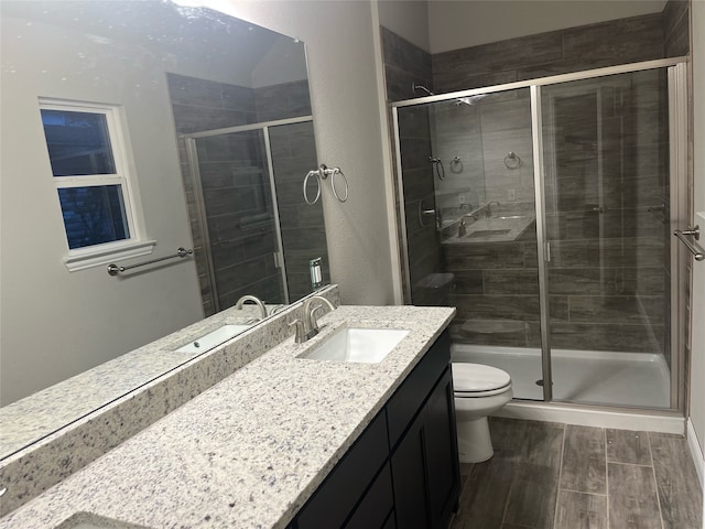 bathroom with wood-type flooring, an enclosed shower, toilet, and large vanity