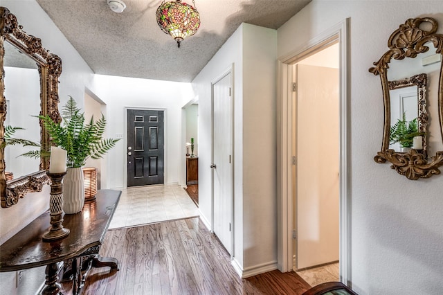 interior space with a textured ceiling, light wood-type flooring, and baseboards