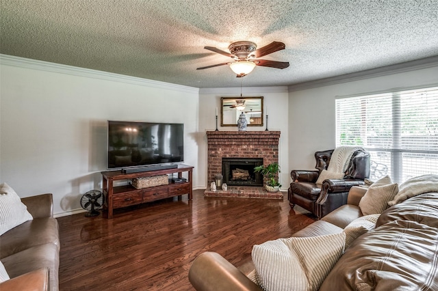 living room featuring ceiling fan, a textured ceiling, ornamental molding, a brick fireplace, and dark wood-style floors