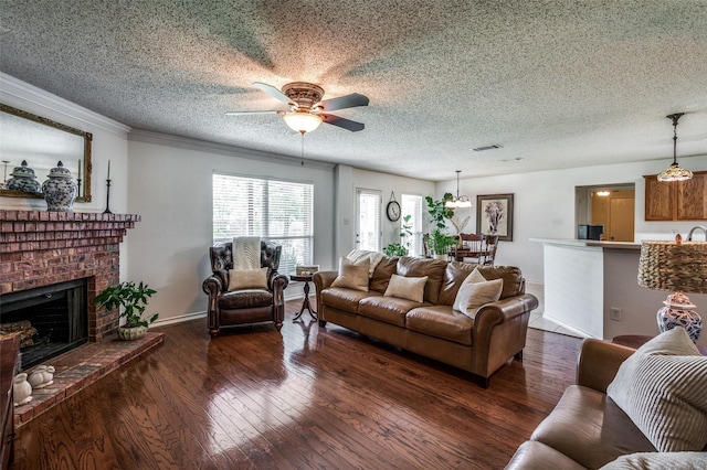 living room featuring a textured ceiling, dark wood-style flooring, a fireplace, a ceiling fan, and crown molding