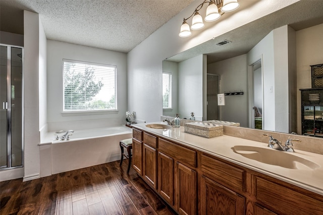 full bath with visible vents, wood finished floors, a garden tub, a textured ceiling, and a sink