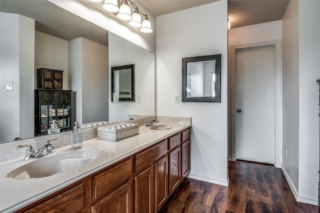 full bathroom featuring double vanity, baseboards, a sink, and wood finished floors