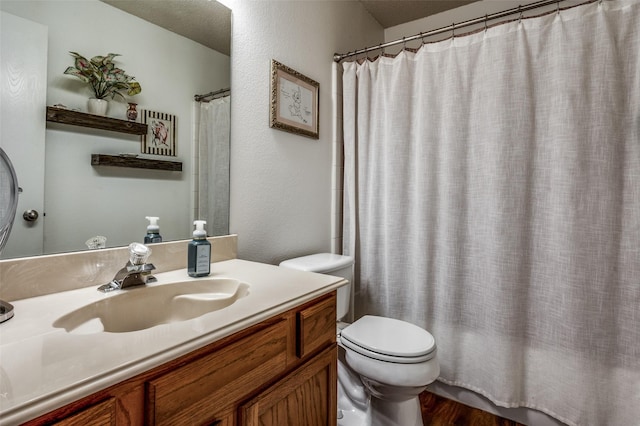 full bathroom featuring shower / bath combo, a textured wall, vanity, and toilet