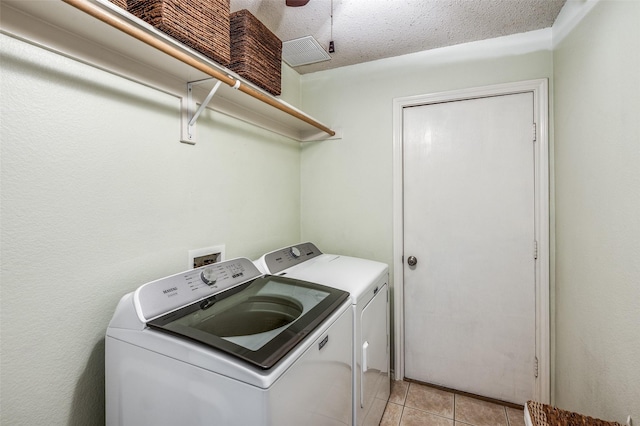 laundry area featuring laundry area, light tile patterned flooring, washer and clothes dryer, and a textured ceiling